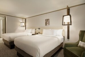 A hotel room with two beds, a nightstand, a lamp, a painting, and a green armchair. - Hilton Garden Inn Newtown Square Radnor (Newtown Square)