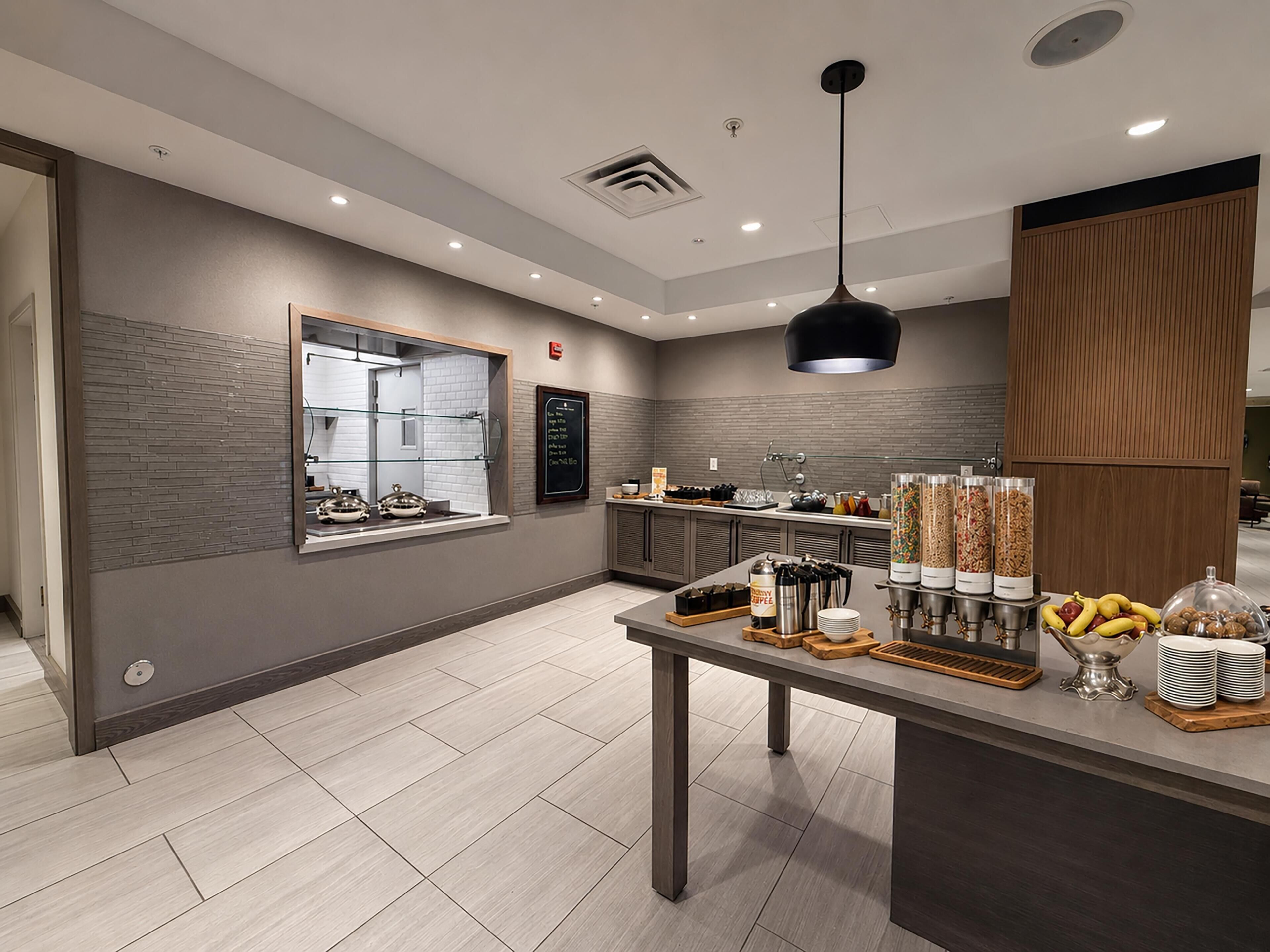 Un café moderne doté d’un comptoir, d’un espace salon et de divers distributeurs de nourriture et de boissons.