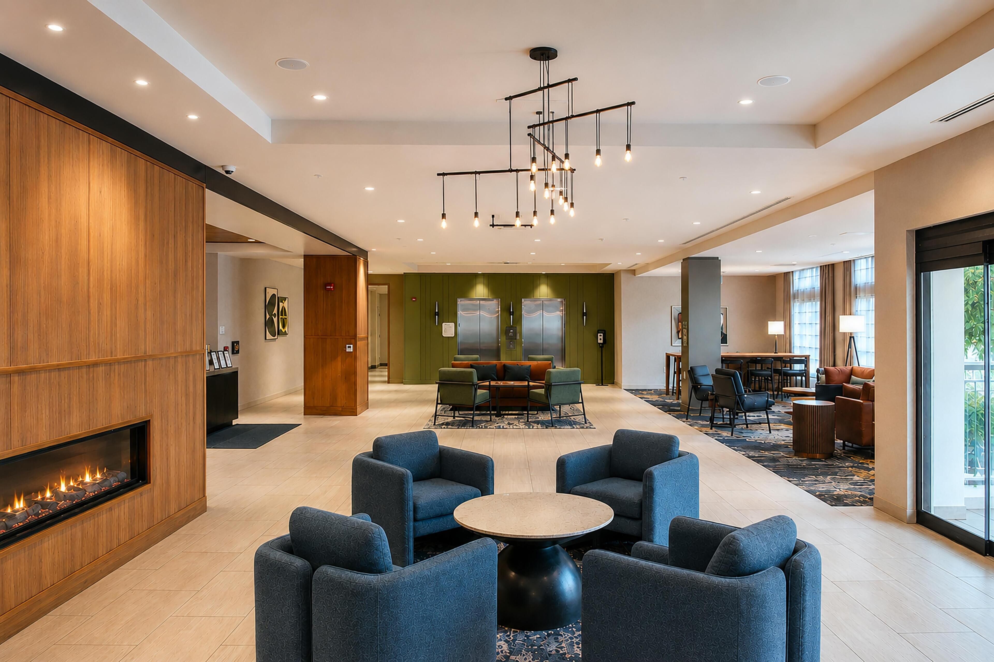 Un hall d’hôtel doté d’une cheminée, d’un coin salon et d’un espace repas.