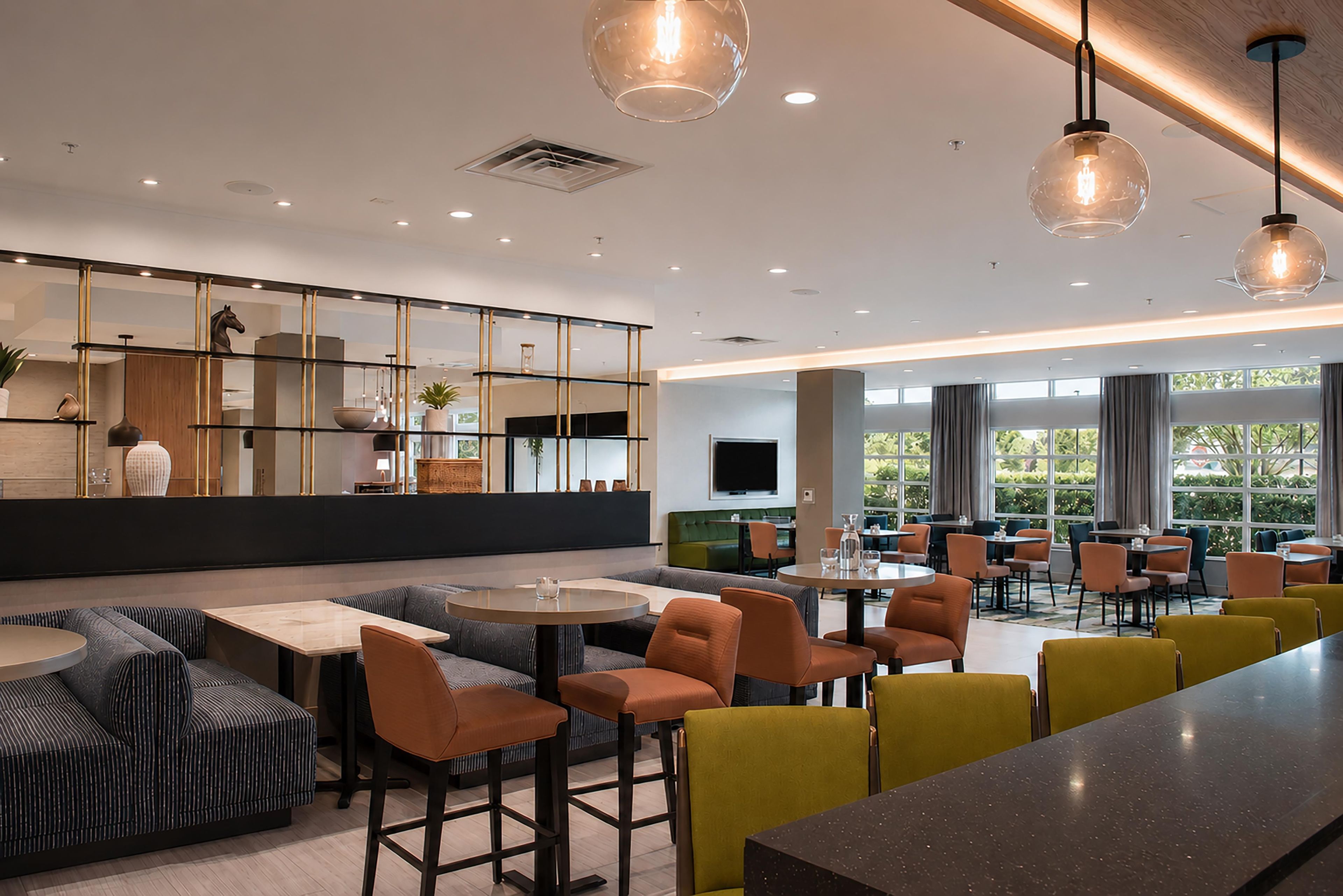 A modern interior with seating areas, a bar, and a large window providing natural light.