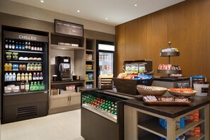A self-service beverage station with chilled drinks, a coffee machine, and a variety of snacks and cookies. - Hilton Garden Inn Newtown Square Radnor (Newtown Square)