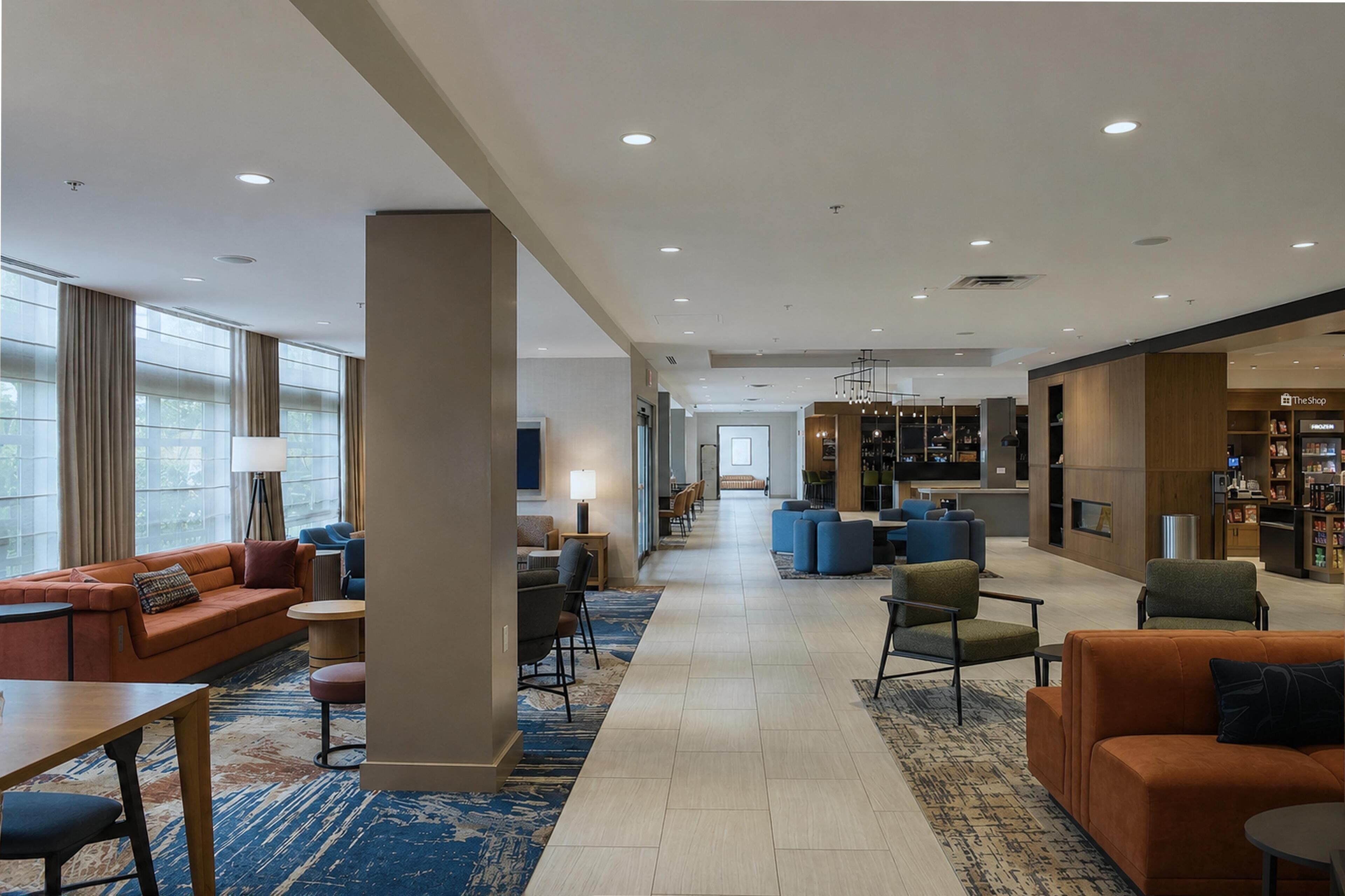 A hotel lobby with seating areas, a reception desk, and a store named 'The Shop'.