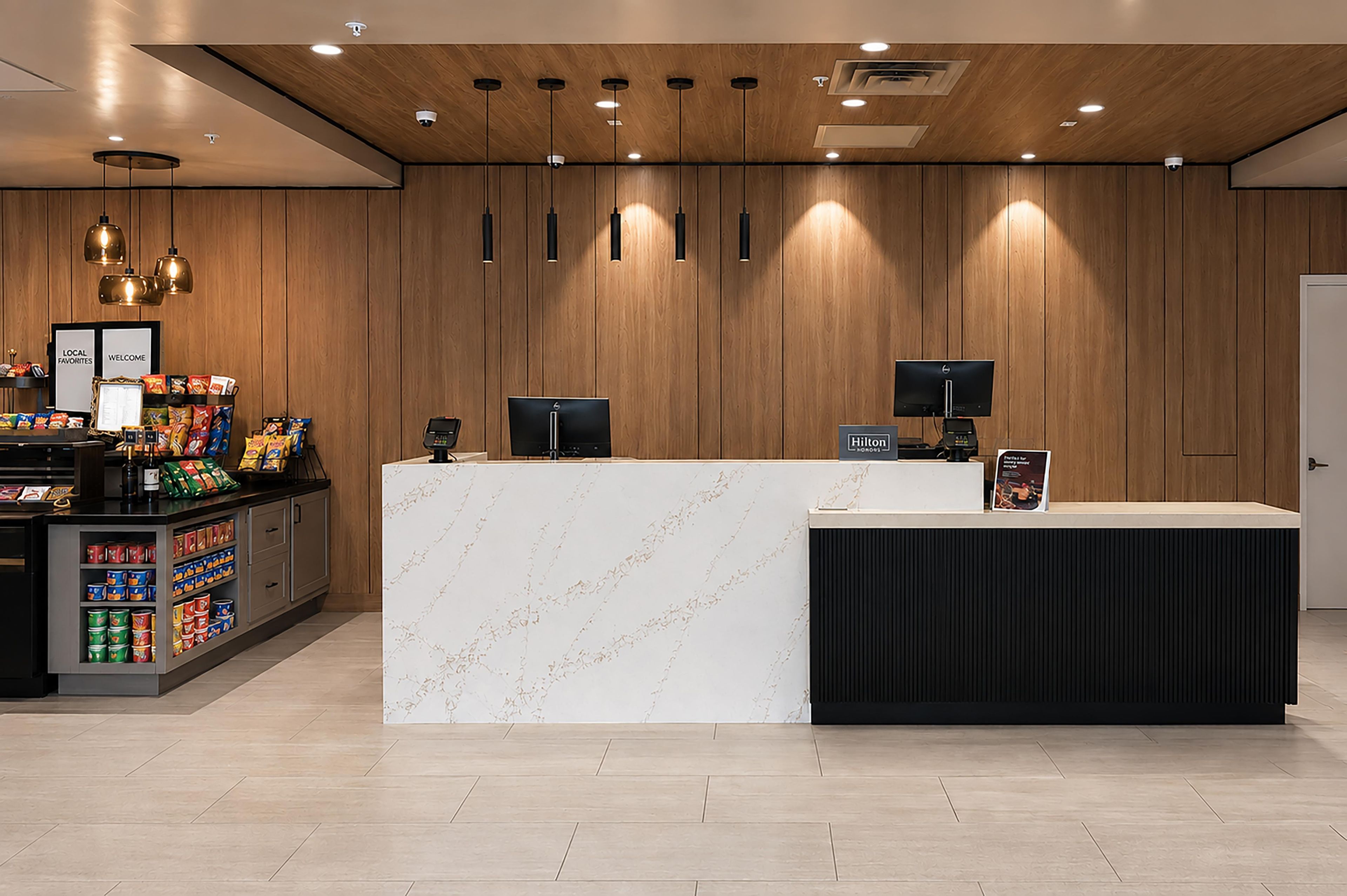 A hotel reception area with a marble counter, a minibar, and a snack display.