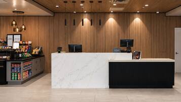 A hotel reception area with a marble counter, a minibar, and a snack display.