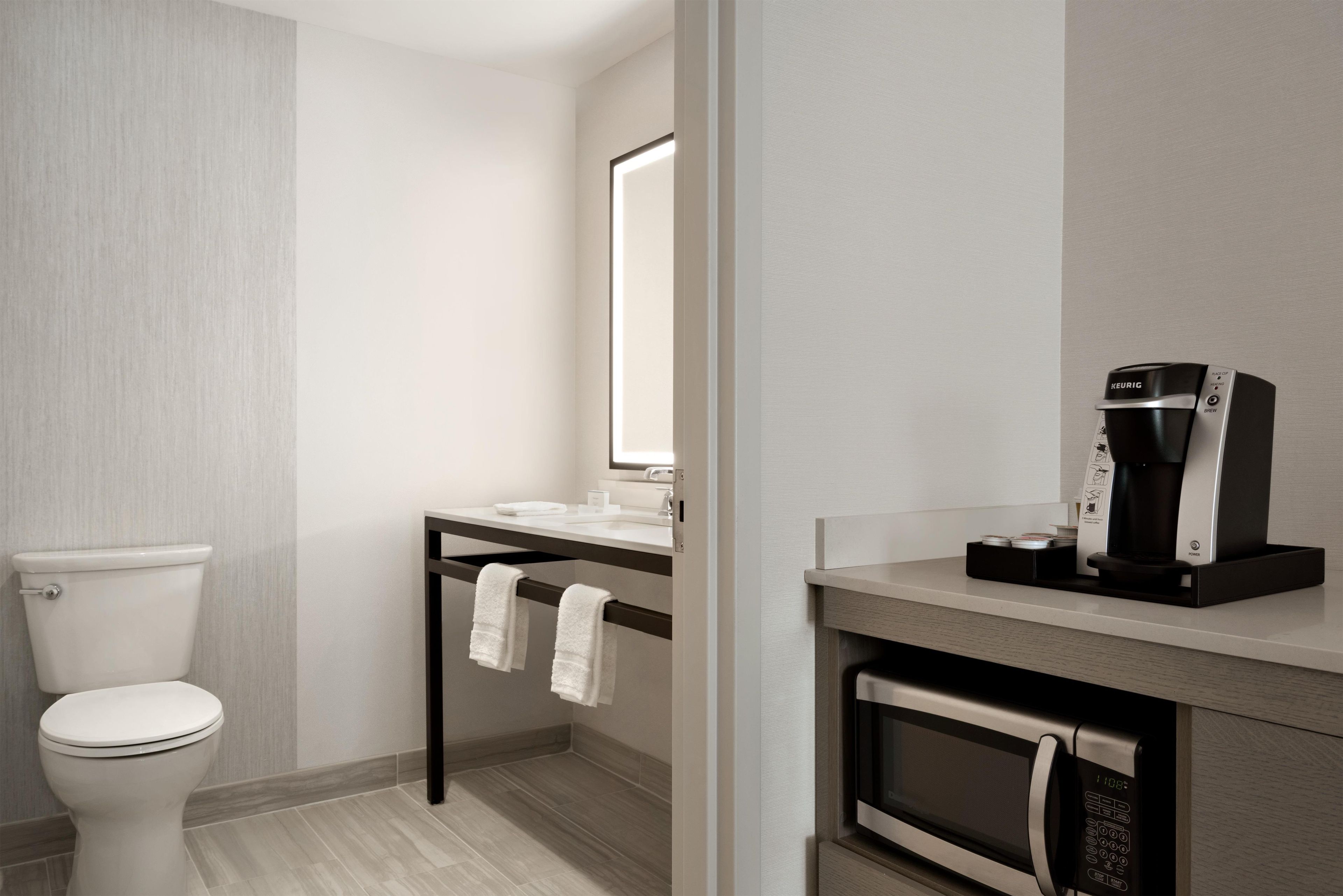 A modern bathroom with a toilet, sink, and coffee maker.