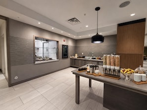 A modern cafe with a counter, seating area, and a variety of food and drink dispensers. - Hilton Garden Inn Newtown Square Radnor (Newtown Square)