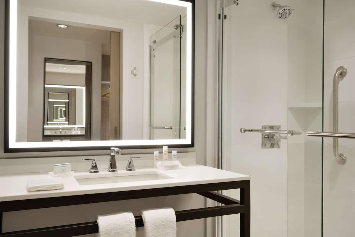Un bany modern amb un mirall gran, un lavabo blanc i una cabina de dutxa de vidre.