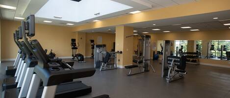 A gym with treadmills, weight machines, and a large mirror.
