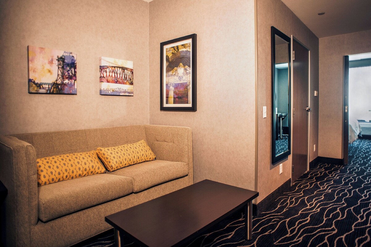 Ein Hotelzimmer mit einer Couch, einem Couchtisch und drei gerahmten Kunstwerken an der Wand.