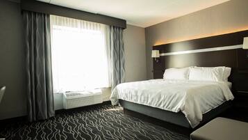 A hotel room with a bed, a bedside table, a lamp, and a window with curtains.