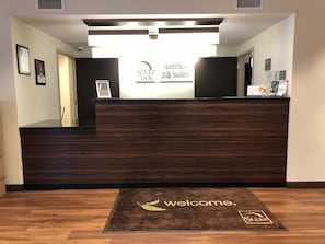 A reception desk with a 'Welcome' mat and a 'Sleep Inn Suites' sign. - MainStay Suites St Louis Airport (Bridgeton)