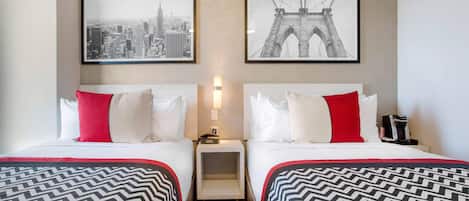 Une chambre d’hôtel avec deux lits, chacun recouvert d’une couvre-lit à motifs, une table de chevet entre les deux, et deux tableaux encadrés au mur.