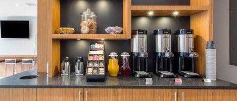 Una cucina moderna con un angolo caffè, dotato di diverse macchinette e una vasta scelta di bevande.