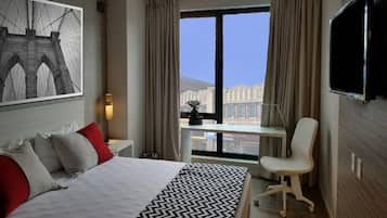 Een hotelkamer met een groot bed, een bureau met stoel, een televisie en een raam met gordijnen.