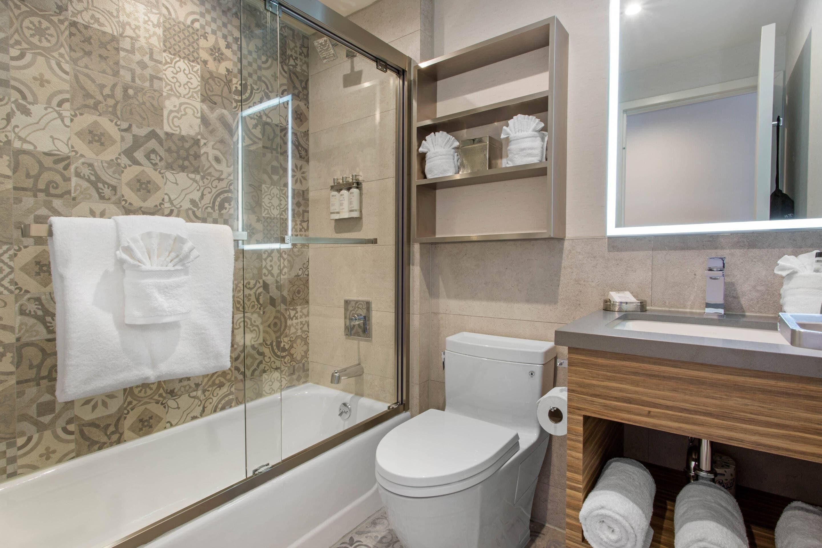 A modern bathroom with a glass-enclosed shower, a toilet, and a vanity with a mirror.