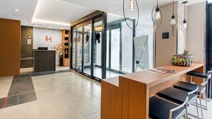 Un moderno vestíbulo de hotel con mostrador de recepción, zona de estar y ventanas amplias que ofrecen vistas.