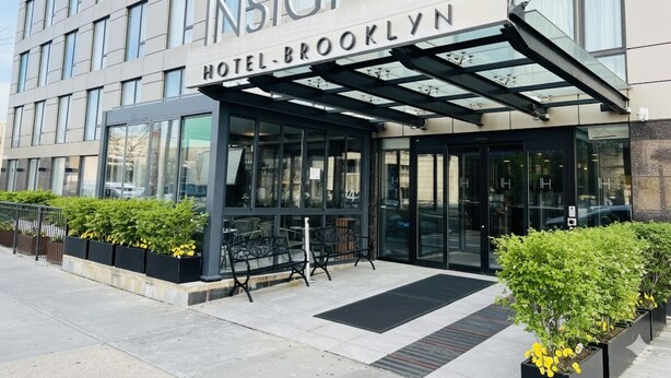 Exterior del Hotel Brooklyn, con un diseño moderno, ventanas amplias y una zona de acceso cubierta.