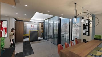 Rebedor modern d'hotel amb una taquilla d'admissió, una paret de vidre amb vista a la ciutat, una zona de menjador de fusta amb tamborets i un penjador.