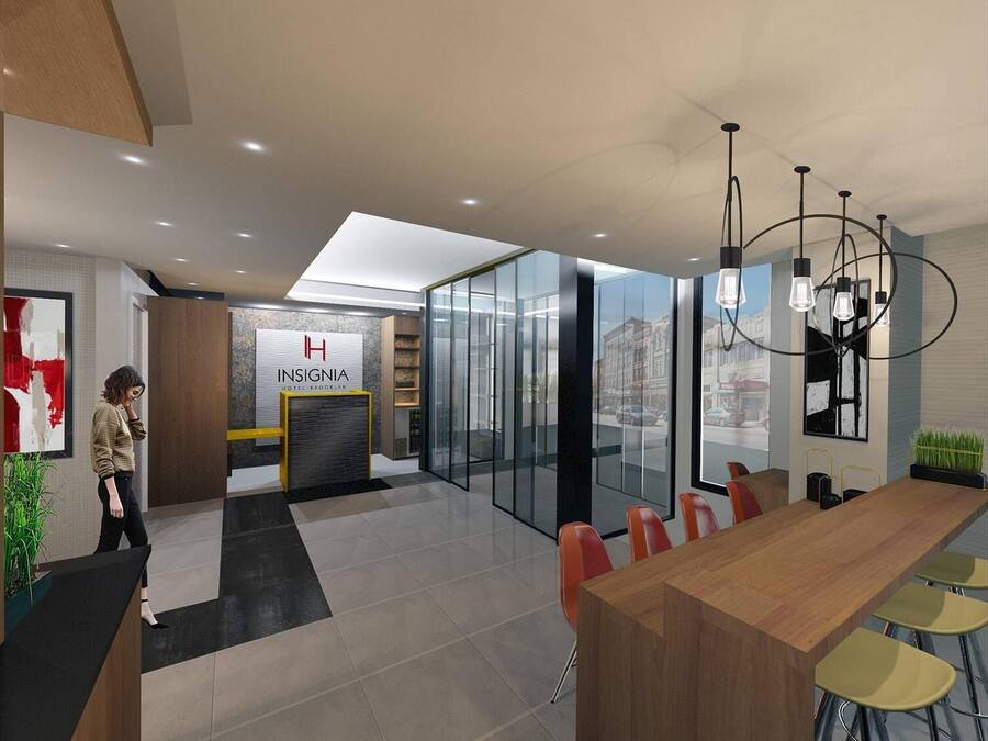 A modern hotel lobby with a reception desk, a glass wall with a city view, a wooden dining area with bar stools, and a chandelier.