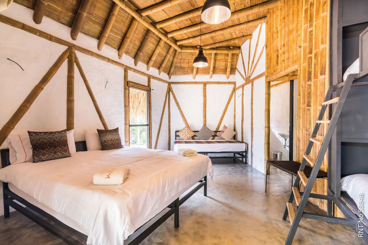 A room with a bed, a bench, and a ladder.