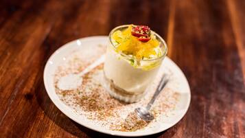 Postre en un plato blanco con una cuchara, sobre una mesa de madera.