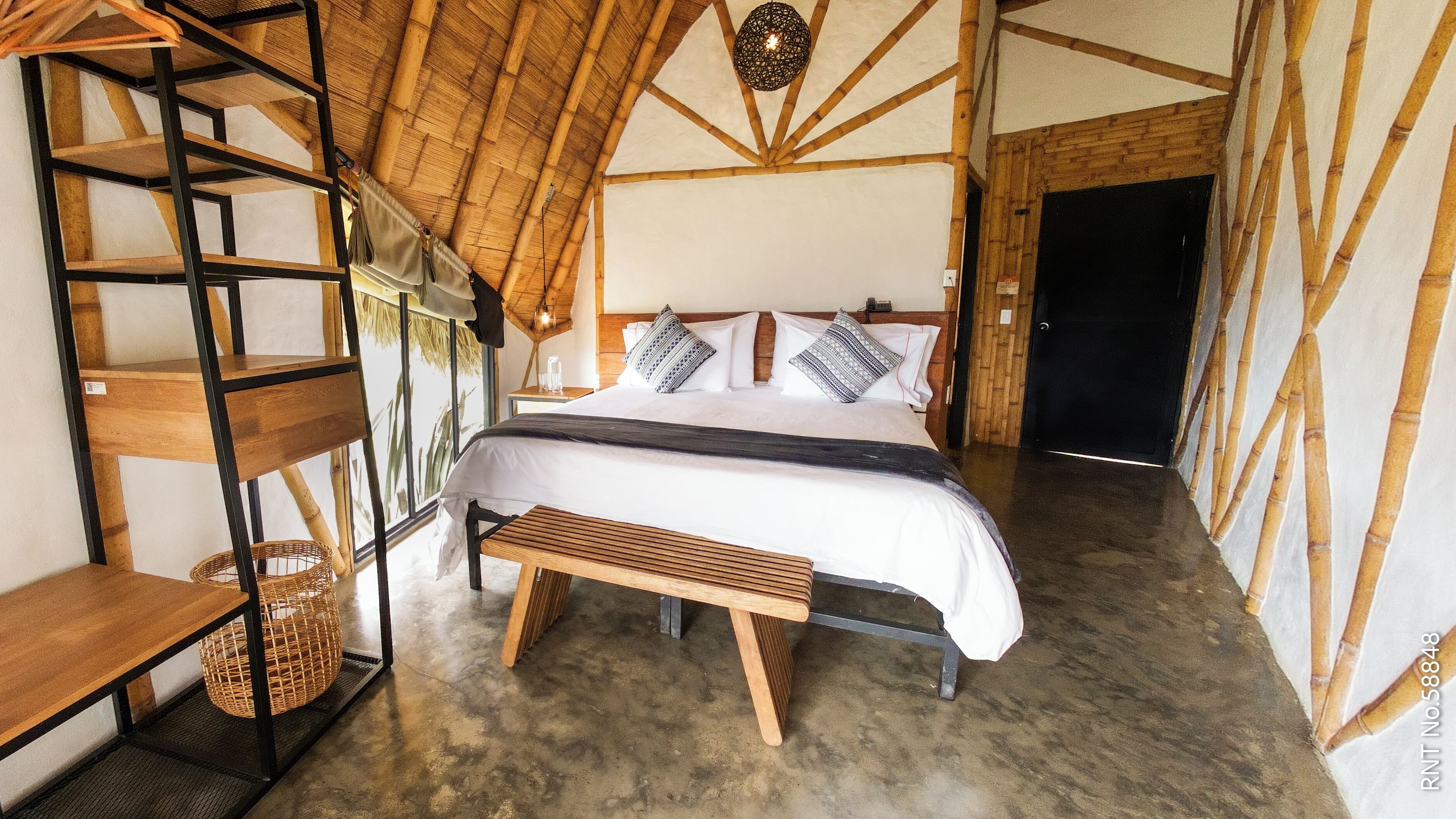 A room with a bed, a wooden bench, a shelf, and a basket.