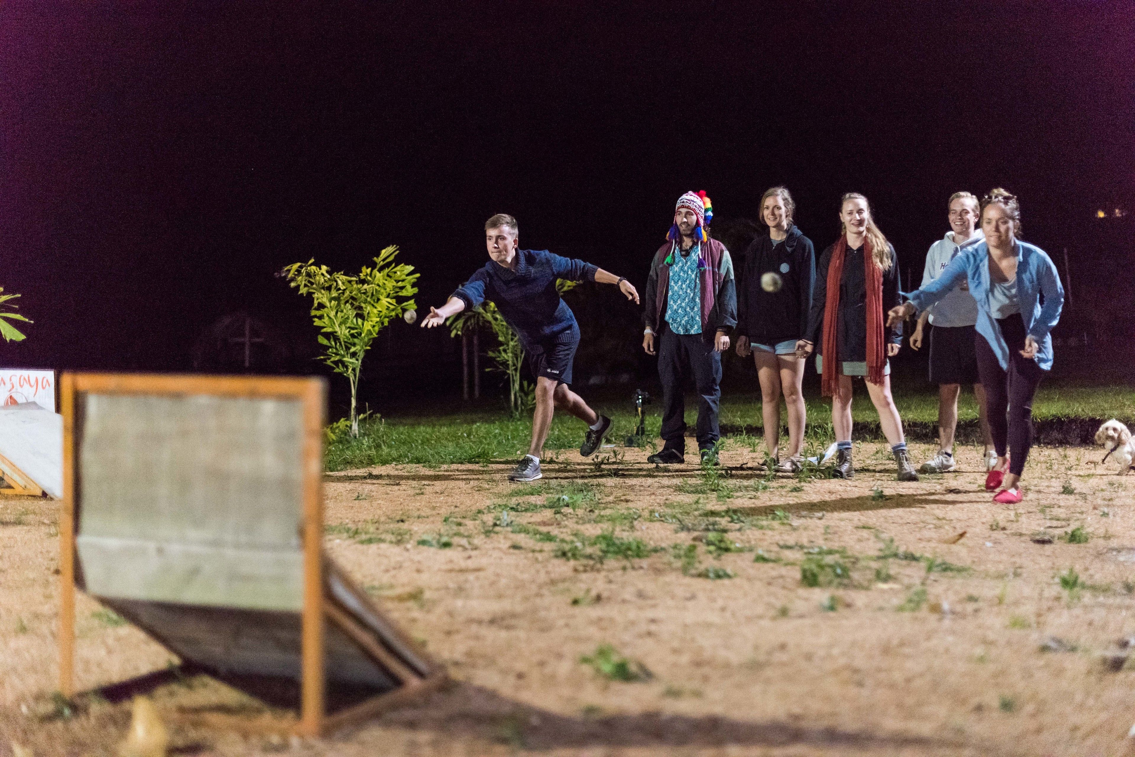 A group of people playing a game outdoors at night.