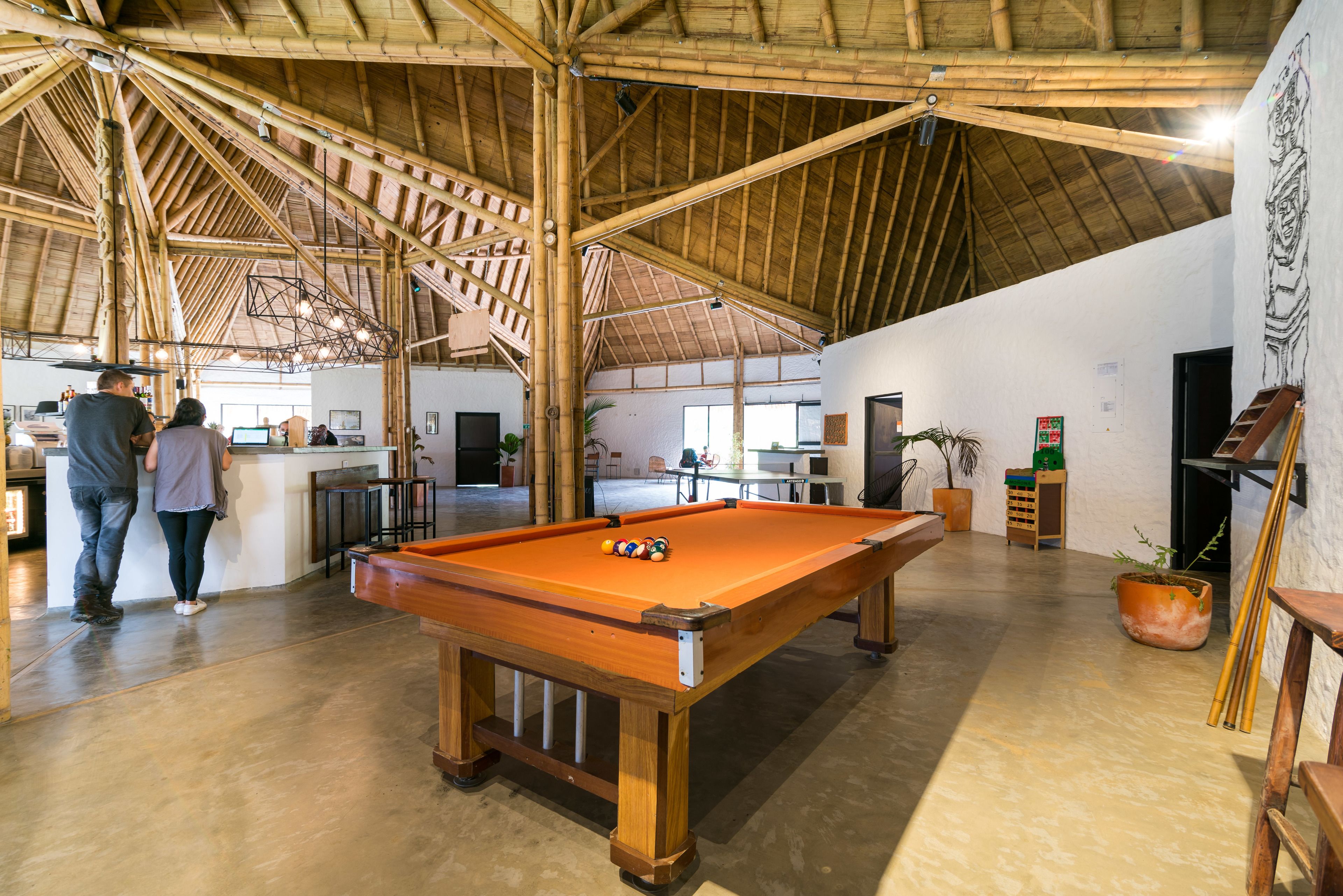 Um espaço amplo e interno com mesa de bilhar, vigas de madeira e teto alto.