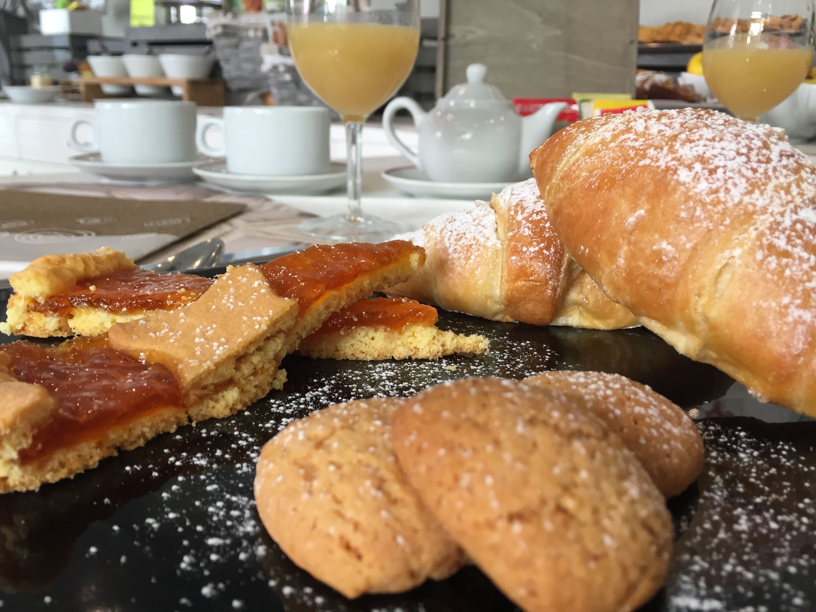 Ein Tisch mit Gebäck, einem Teekännchen und Gläsern mit einem gelben Getränk.