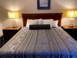A neatly made bed with a patterned bedspread, two bedside lamps, and a framed picture on the wall.
