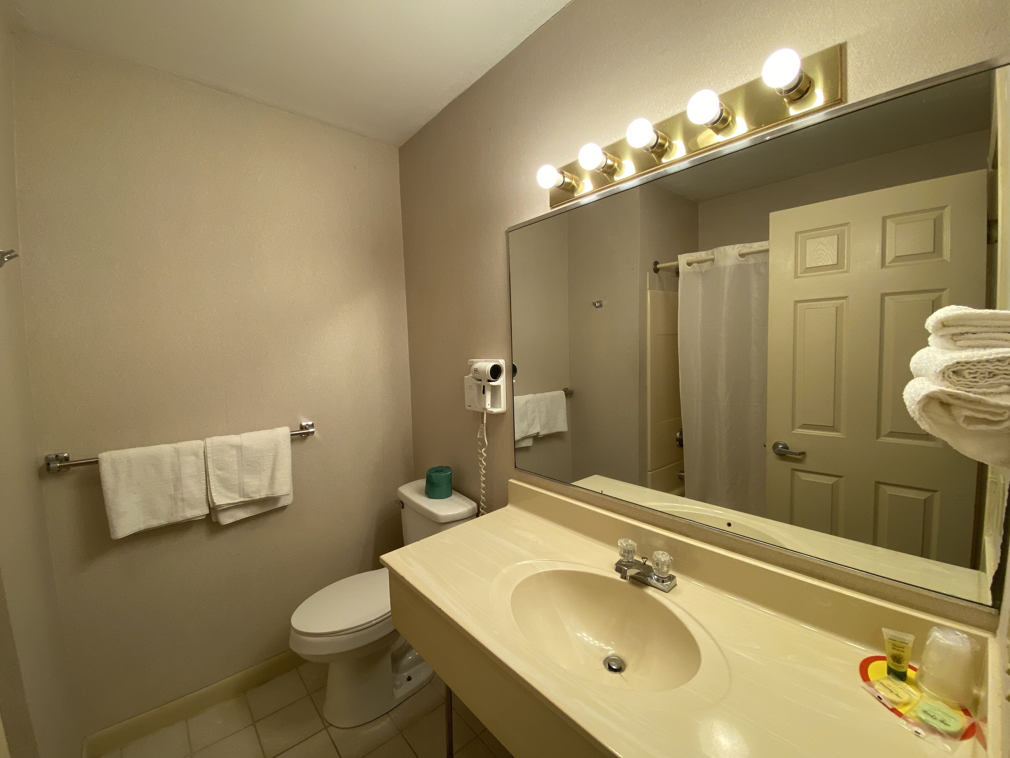 Une salle de bain avec un lavabo, un miroir et des toilettes.