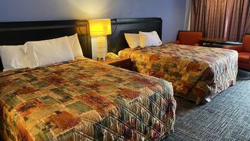 Ett hotellrum med två sängar, ett nattduksbord med en lampa, en telefon och ett litet bord.