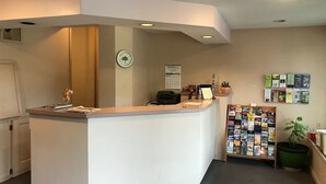A reception desk with a clock, a calendar, and a bulletin board with pamphlets. - Economy Lodge (Fiskdale)