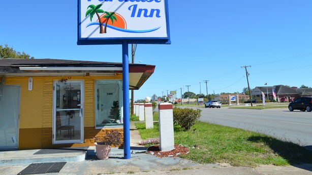 A sign for Paradise Inn with a palm tree and ocean wave design. - Paradise Inn (Bay City)
