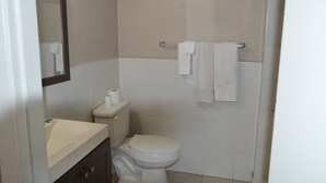 A small, clean bathroom with a toilet, sink, and towel rack. - Paradise Inn (Bay City)