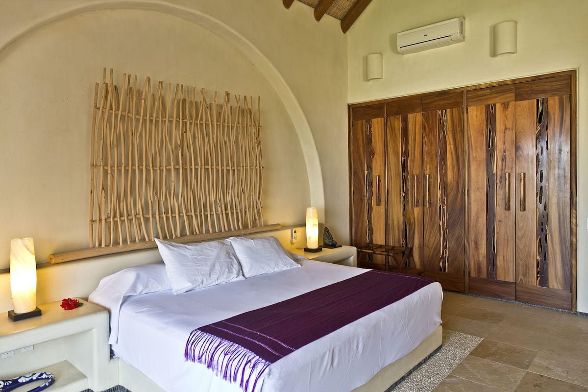 Un dormitorio con una cama grande, un armario de madera y una lámpara fijada a la pared.