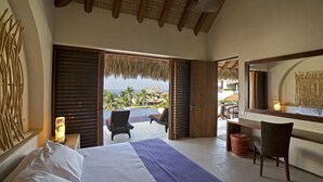 Habitación de hotel con cama, escritorio y vista a la playa.