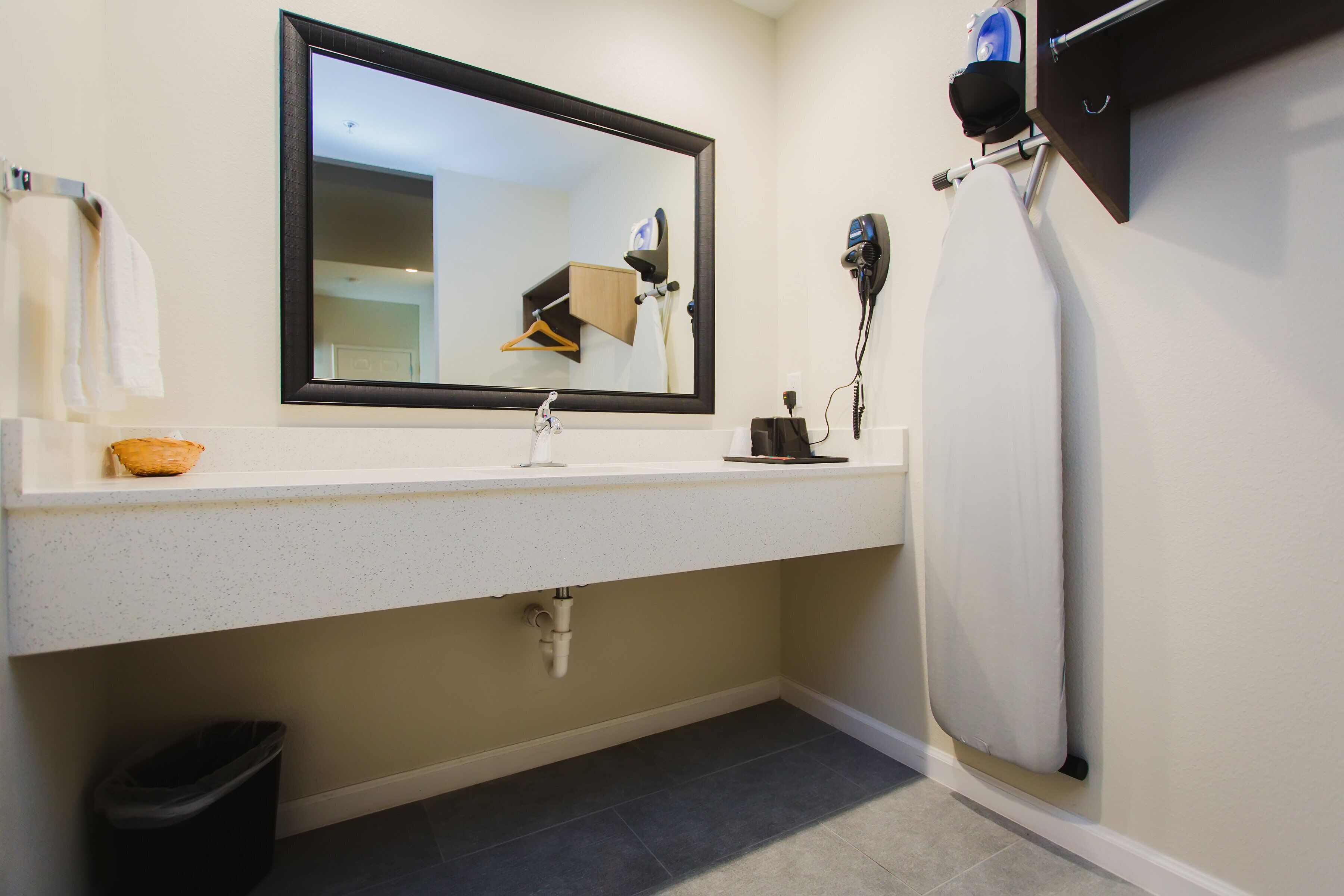 A bathroom with a white sink, a mirror, a hairdryer, and a towel rack.