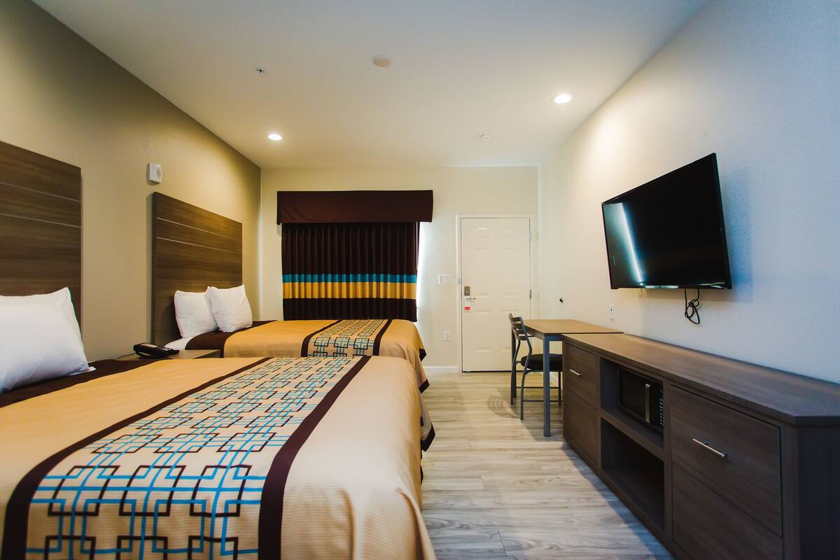 A hotel room with two beds, a TV, a desk, and a wardrobe.