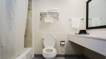 A bathroom with a toilet, a towel rack with towels, a mirror, and a shower curtain.