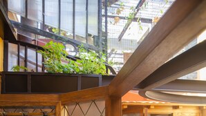 Una habitación con un separador de madera, una vitrina de copas de vino y vistas a un balcón con plantas y flores.