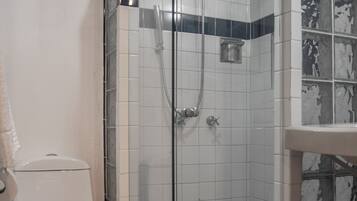 Ein Badezimmer mit einer Duschkabine, einer Toilette und einem Waschbecken mit Marmorablagefläche.