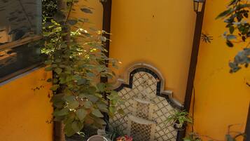 A small outdoor seating area with a table and two chairs, surrounded by yellow walls and a tiled floor.