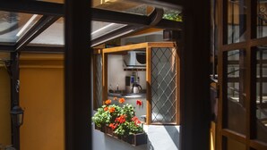 Vista a través de una ventana de una cocina con microondas, cafetera y plantas en macetas.