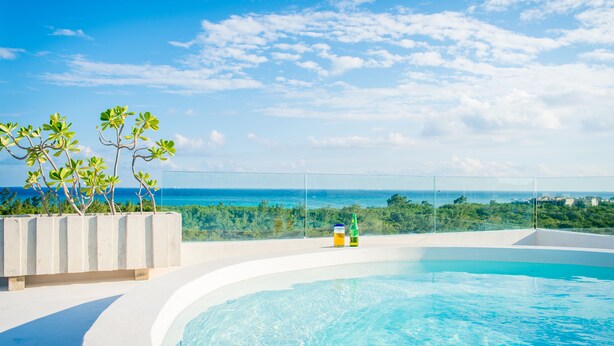 A clear blue sky, a swimming pool, and a view of the ocean. - Suites Cielo y Mar (Playa del Carmen)