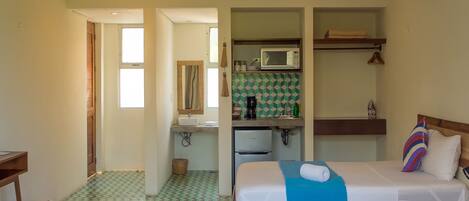 A hotel room with two beds, a bathroom, and a kitchenette.