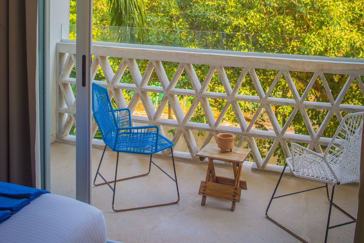 Un balcon avec un lit, deux chaises et une petite table.