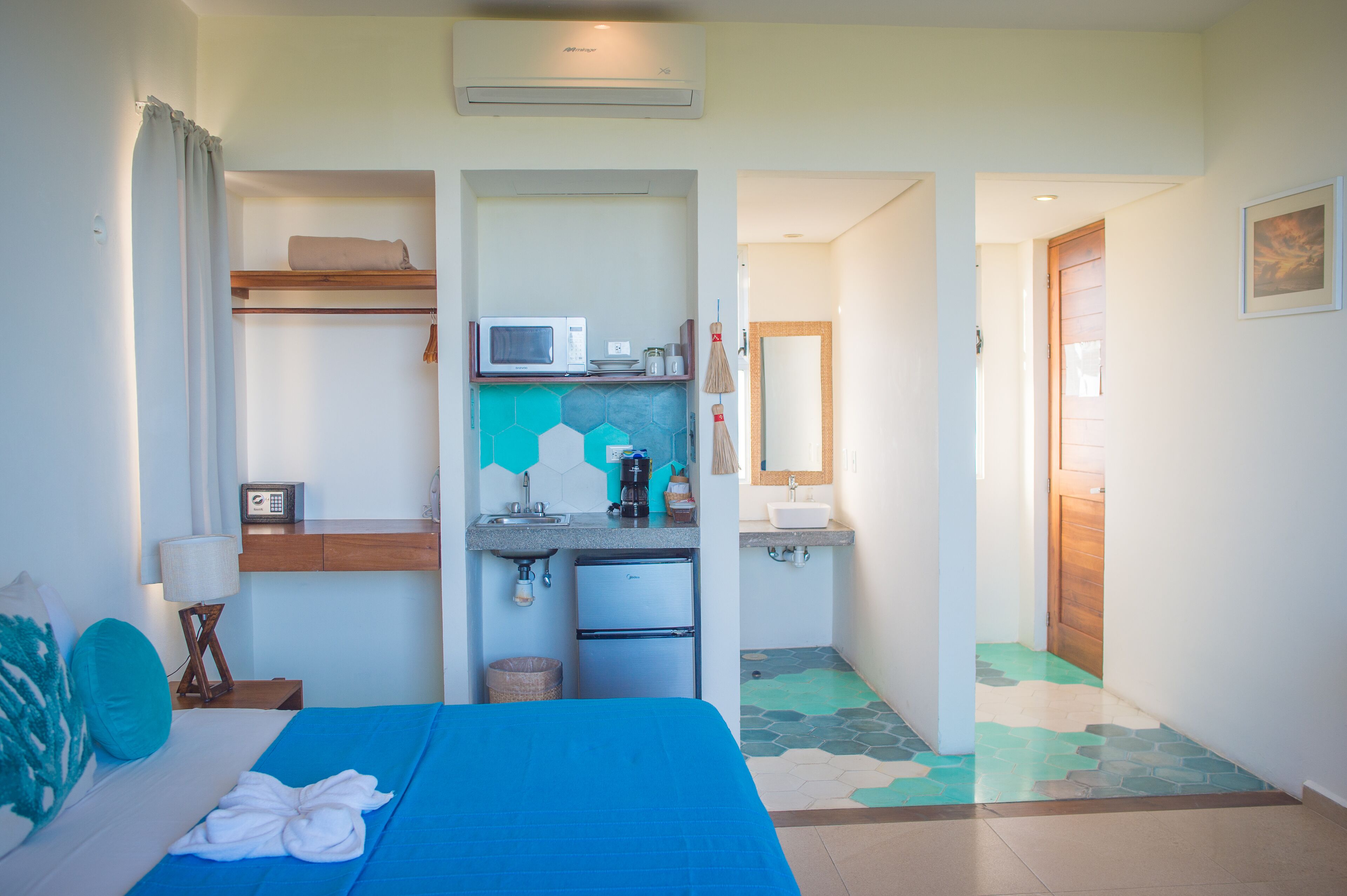 Ein Hotelzimmer mit Bett, einer kleinen Küchenzeile, einem Badezimmer und einem Flur.