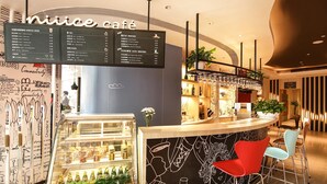 A cafe with a menu board, bar area, seating, and decorative wall art.