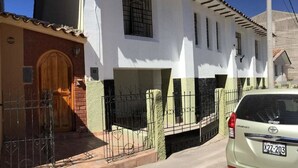 A two-story house with a wooden door and a car parked in front. - Casa Riso Cusco I (Cusco)